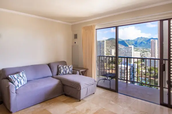 Cozy living area with a sleeper sofa and direct access to the private balcony overlooking Waikiki.