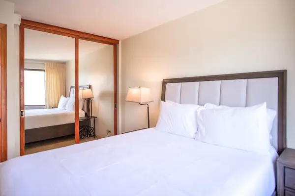 Peaceful bedroom with mirrored closet doors, plush bedding, and ample storage for extended stays.