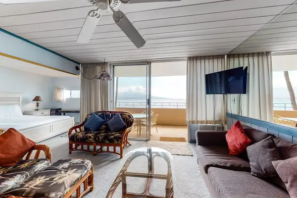 Bright living room with sliding glass doors, abundant natural light, flat screen tv and a comfortable sofa bed for extra guests.