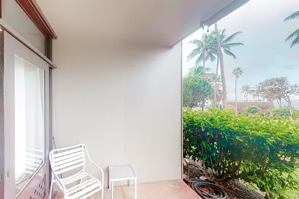 Covered patio offers outdoor seating beside tropical greenery and palms