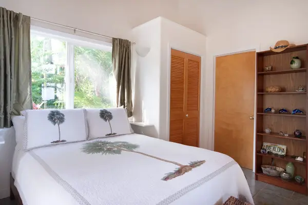 Sunlit Guest Bedroom with Palm Quilt Bedding & Bookshelf