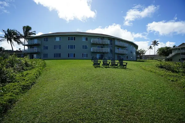 Building exterior with lush grounds and ocean backdrop
