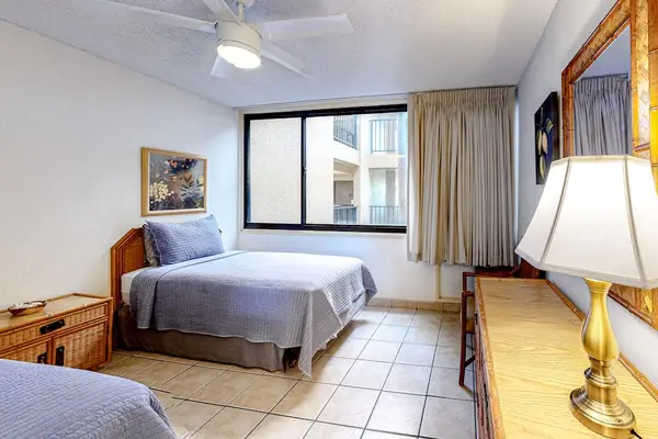 Comfortable twin bedroom with dresser storage, a large mirror, and plenty of natural light