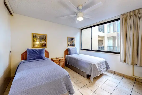 Two comfortable twin beds with a window overlooking the resort grounds