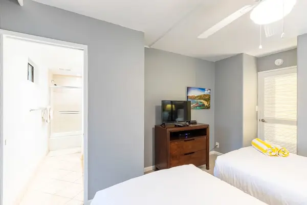 Guest bedroom with two single beds, flat screen tv and lanai access.
