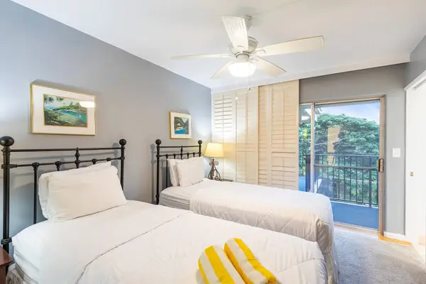 Guest bedroom with two single beds, flat screen tv and lanai access.