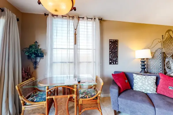 Glass-Top Dining Table with Wicker Seating next to Cozy Living Area