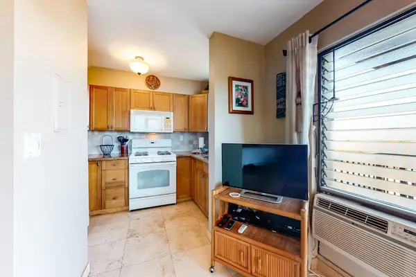 Kitchenette Area with TV Setup, Wall AC Unit, and Full Gas Range