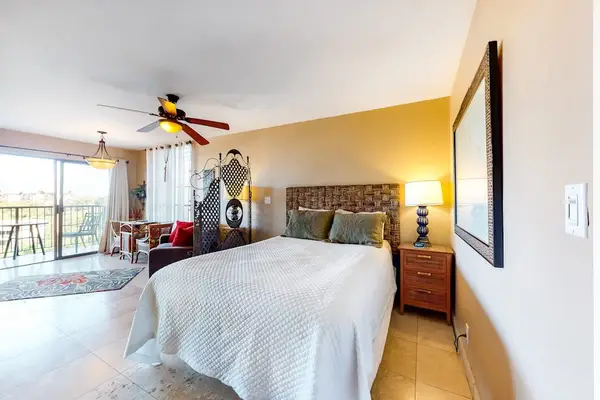 Spacious Studio Bedroom with Bedside Lamp and View toward Balcony