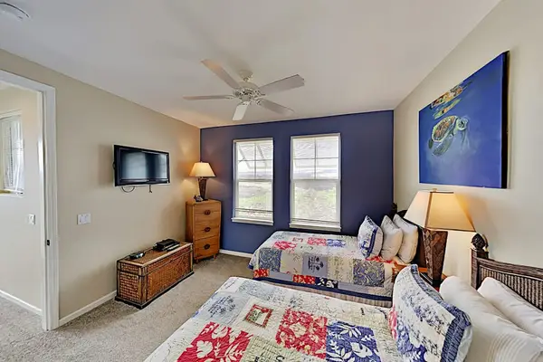 Guest bedroom with two twin beds, flat screen tv and an en-suite bathroom.