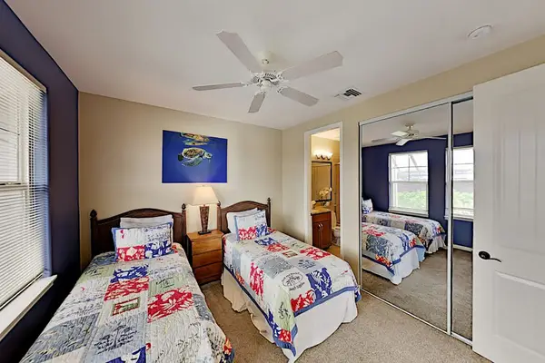 Guest bedroom with two twin beds, flat screen tv and an en-suite bathroom.