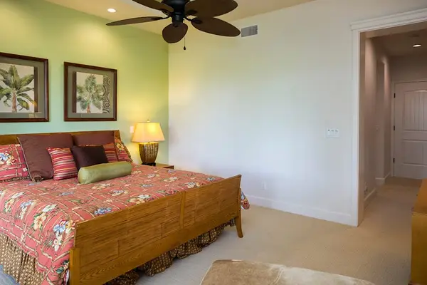 Spacious Primary Suite Bed Area with Tropical Decor & Ceiling Fan