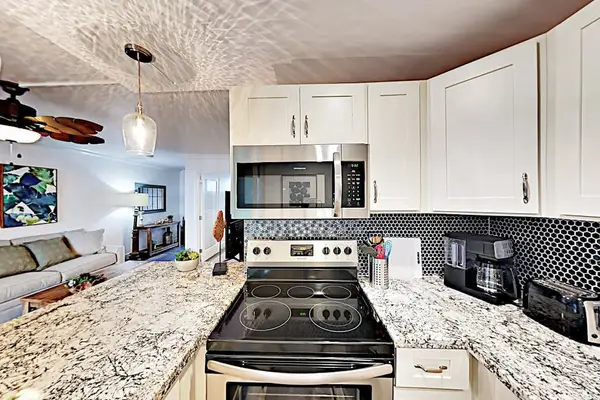 Spotless kitchen showcases ample storage, granite counters, and stylish fixtures