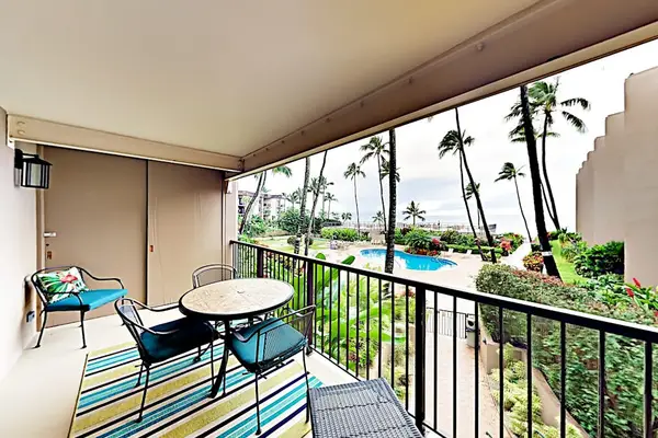 Covered balcony offers outdoor seating, tropical foliage, and ocean views