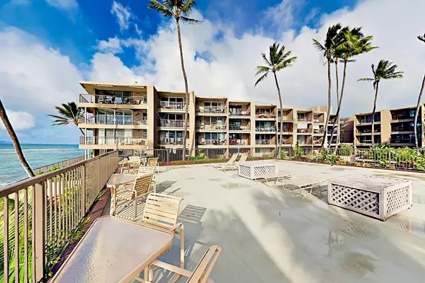 Building exterior features multiple balconies, palms, and tropical landscaping