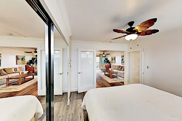 Bright bedroom features a king bed, mirrored closet, and windows