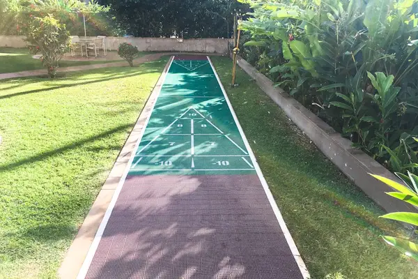 Outdoor shuffleboard court offers recreational fun beside lush tropical gardens