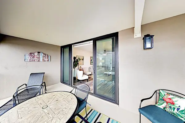 Covered balcony features lounge seating, sliding doors, and garden views