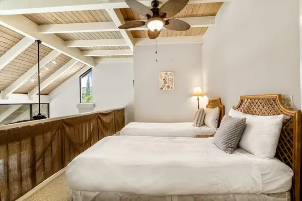 A cozy loft bedroom featuring two comfortable beds and a beautiful vaulted wooden ceiling
