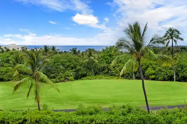A peaceful and scenic landscape featuring rolling green lawns and palm trees