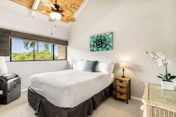 The spacious primary bedroom featuring soaring high ceilings and a plush, comfortable bed
