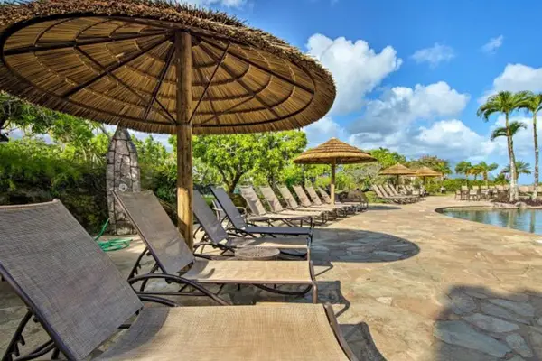 Poolside loungers beneath thatched umbrellas invite relaxing island afternoons outdoors