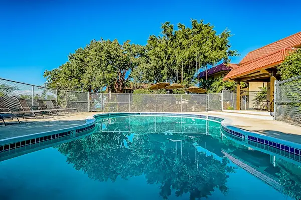 Clear Outdoor Swimming Pool with Fenced Perimeter and Shaded Pavilion View