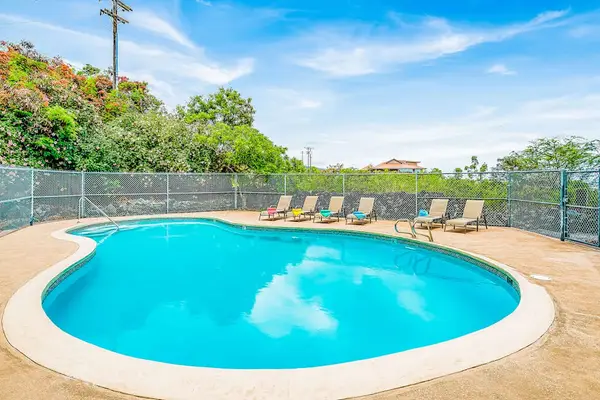 Curved Outdoor Swimming Pool with Paved Deck and Fenced Enclosure