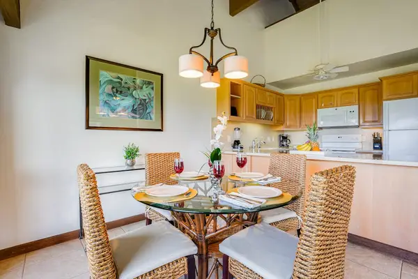 Glass-Top Dining Table with Wicker Chairs & Overhead Modern Chandelier
