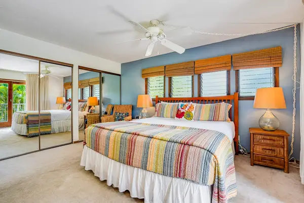 Sunlit Bedroom with Mirrored Closet Doors & Colorful Tropical Bedding