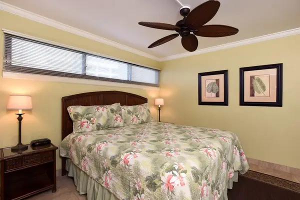 Tropical-themed bedroom that features a ceiling fan with palm-leaf blades.