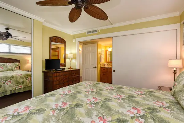 Tropical-themed bedroom that features a ceiling fan with palm-leaf blades.