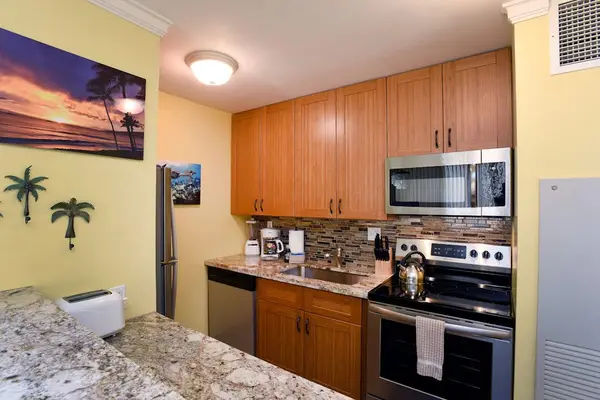 Private kitchen features warm wood cabinets and a stainless steel refrigerator.