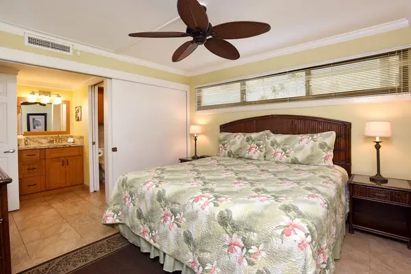 Tropical-themed bedroom that features a ceiling fan with palm-leaf blades.