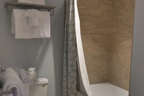 Spotless bathroom includes shower, fresh towels, and clean tiled walls nearby