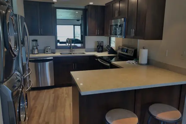 Modern kitchen features dark cabinetry, stainless appliances, and breakfast island