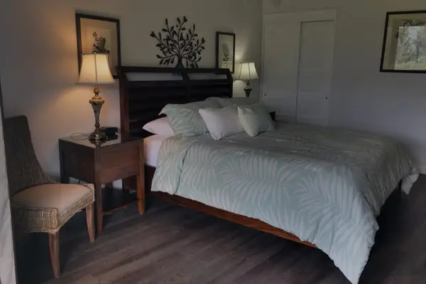 Bedroom features comfortable bedding, bedside lamps, and balcony access