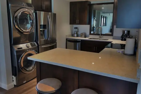 Washer and dryer area includes countertop, cabinetry, and modern appliances