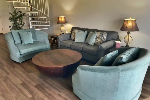 Comfortable living room offers sofas, lamps, and warm wood flooring