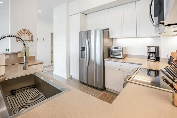Well-lit kitchen layout complete with coffee maker, toaster, and modern under-cabinet lighting