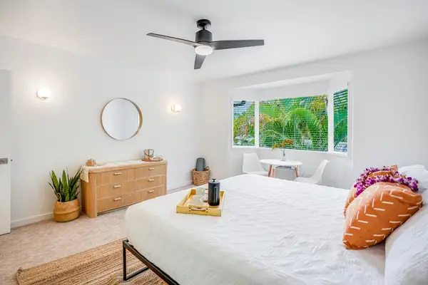 Spacious primary bedroom with king bed, plush bedding, and serene tropical decor