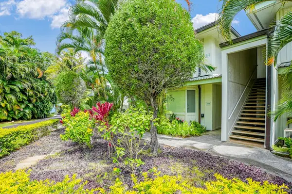Welcoming condo entrance with private staircase and lush tropical flora