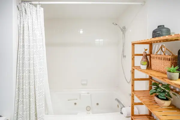 Full bathroom equipped with a shower/tub combination and charming tropical shelving