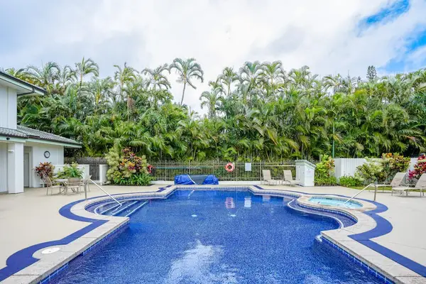 Relaxing outdoor swimming pool surrounded by tropical palm trees and lounge seating