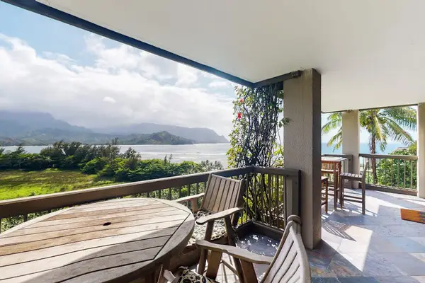 Covered balcony overlooks fields, mountain scenery, and distant ocean waters