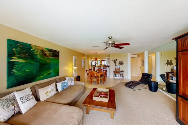 Spacious living area includes seating, ceiling fan, and ocean views