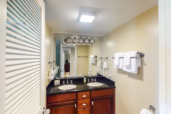 Bathroom vanity includes double sinks, mirrored storage, towels, and accessories