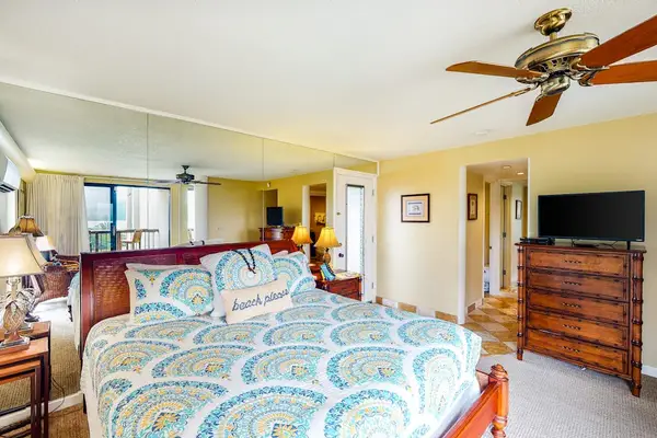 Cozy studio showcases patterned bedding, dresser, ceiling fan, and artwork