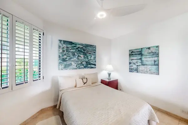 Bright bedroom provides peaceful bedding, artwork, and natural window light