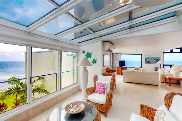 Sunroom lounge features glass walls, relaxed seating, and garden views